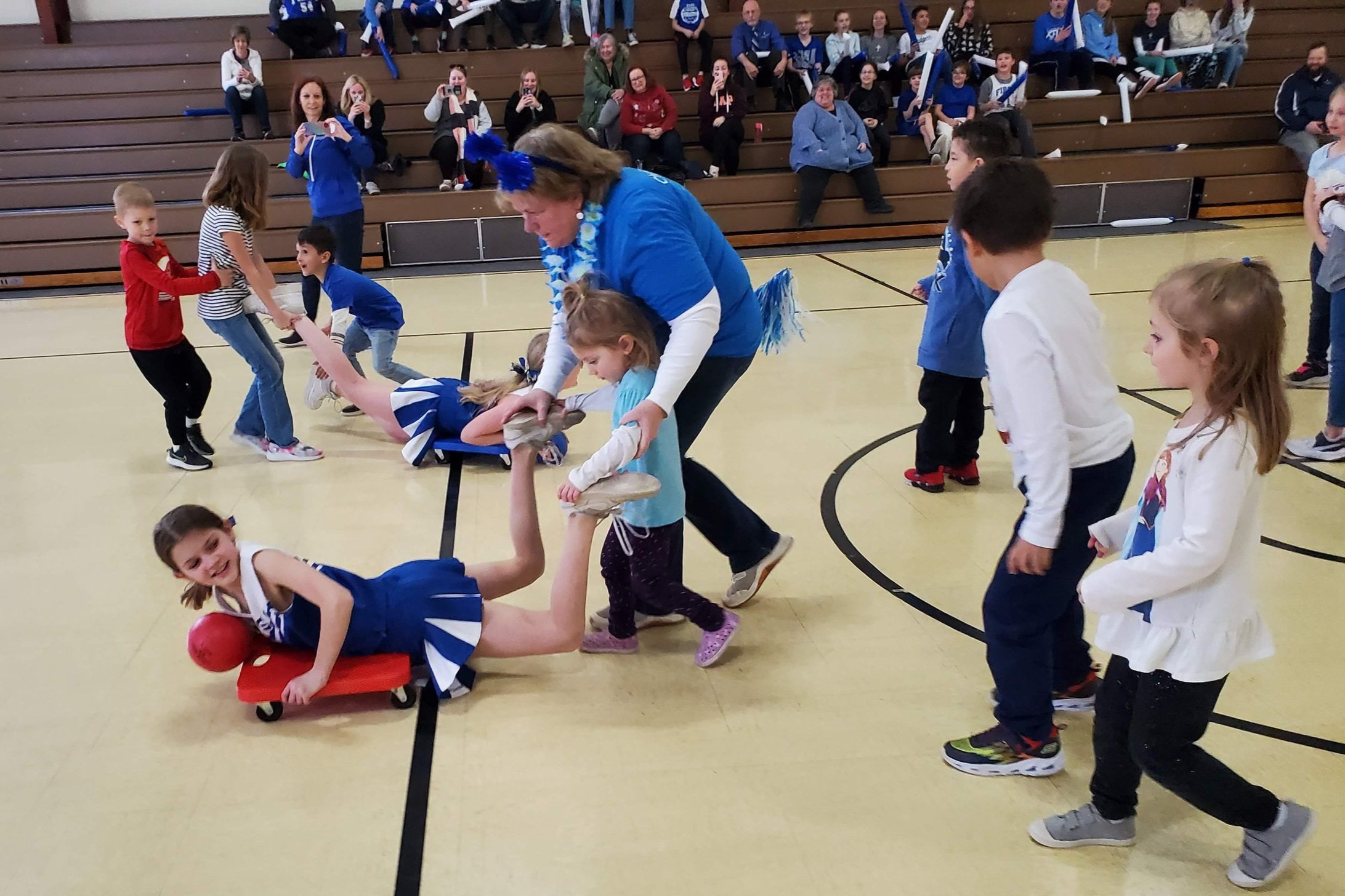 Students racing on scooter boards in the gym