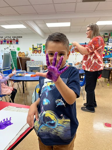 Student showing a purple painted hand during an art project